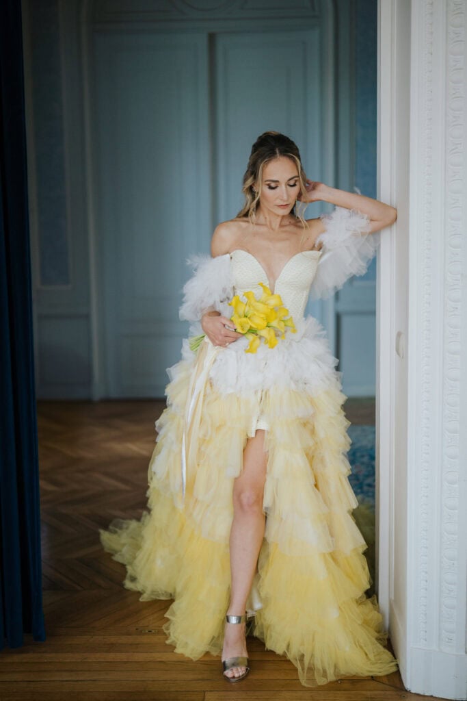 Elegant bride in a yellow tulle wedding gown holding calla lily bouquet at Theatre of Real Life.