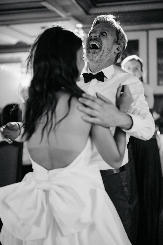 Happy couple dancing at wedding reception, black and white portrait, emotional celebration, romantic moment, dance floor, elegant attire, joyful atmosphere.