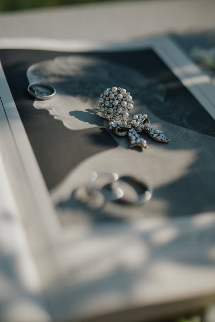 Shiny pearl and rhinestone jewelry on a black-and-white photograph, symbolizing real-life moments and personal stories.