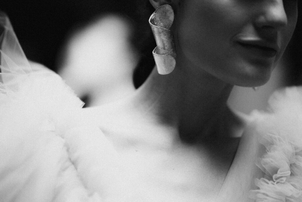 Vintage black and white image of a woman wearing a bold earring and fluffy attire, evocative of theatrical performance and real-life storytelling.