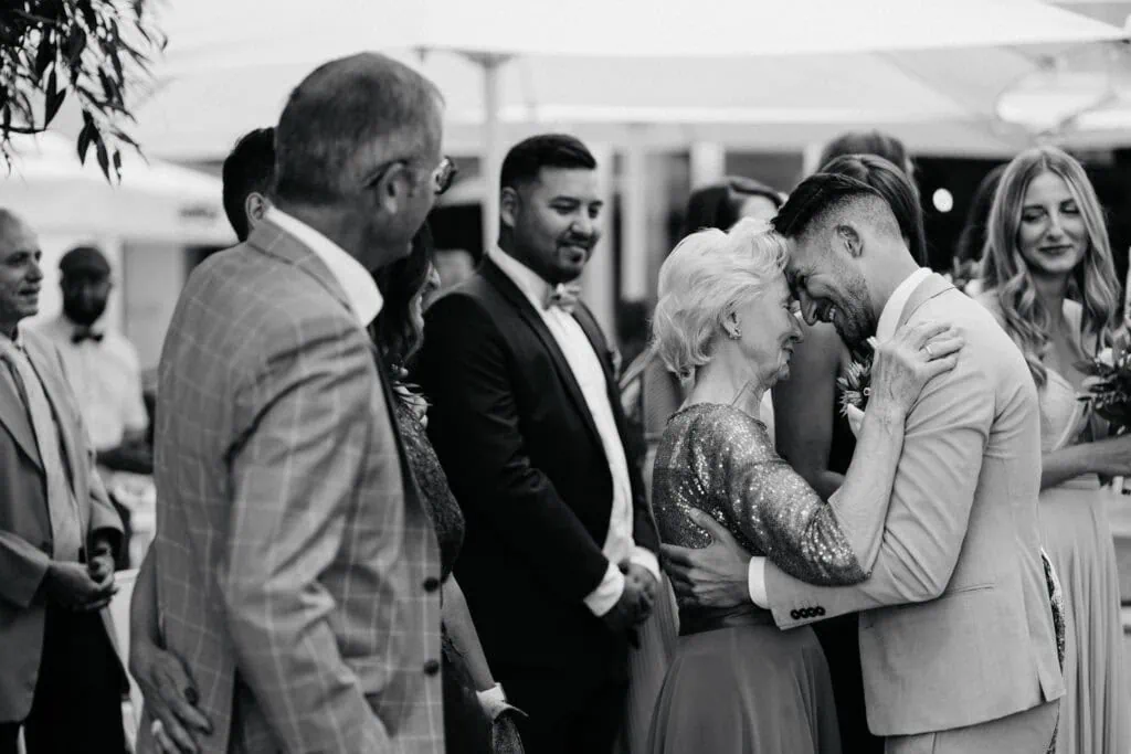 Happy groom and his grandmother sharing a joyful moment amid family and friends outdoors