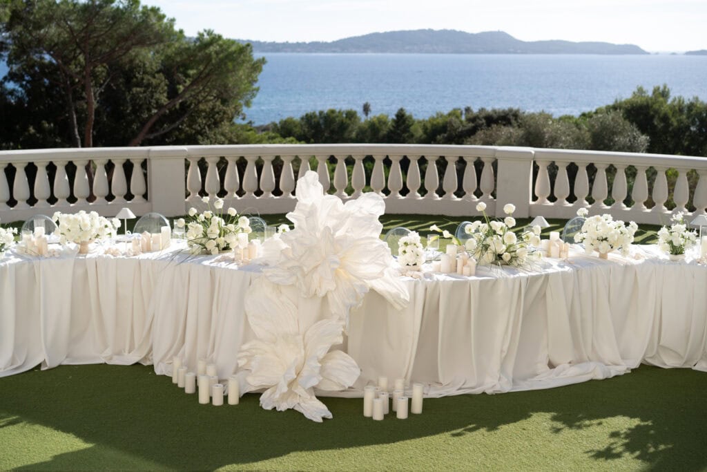 Eleganter Hochzeitsempfang im Freien mit weißen Blumenarrangements, Kerzen und einer malerischen Kulisse mit Meerblick in der Castel Bay.