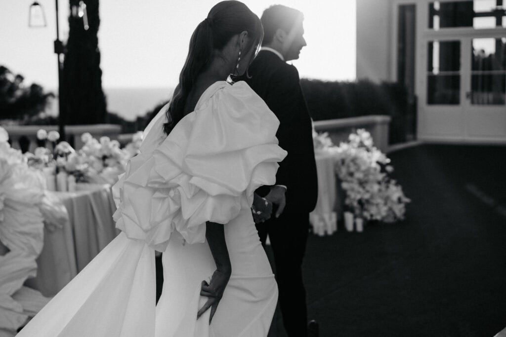 Elegantes Hochzeitspaar in Schwarz-Weiß, das einen innigen Moment während ihrer Zeremonie im Freien bei Sonnenuntergang festhält. Verewigt in Monochrom, das zeitlose Romantik und emotionale Tiefe hervorhebt.