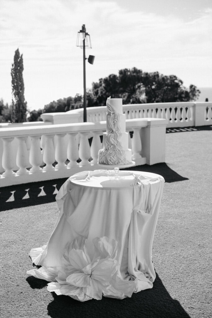 Elegante Hochzeitstorte mit kompliziertem Strudeldesign auf einer Terrasse im Freien.