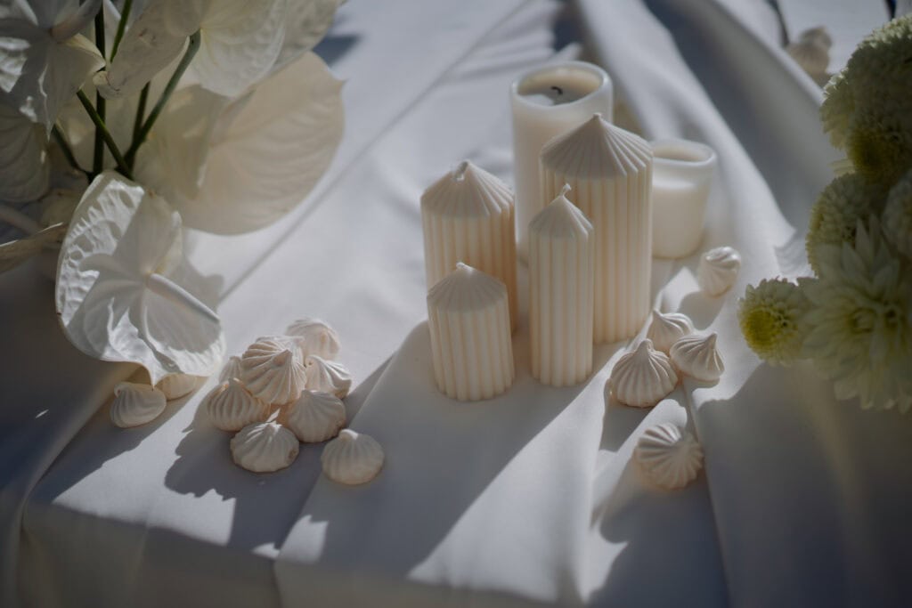 Elegante weiße Kerzen und Blumenarrangements auf einem luxuriös gedeckten Hochzeitstisch.