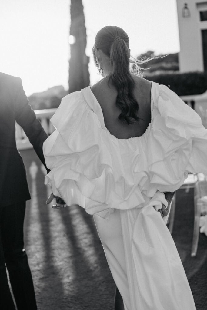 Elegante Braut in einem fließenden weißen Kleid bei Sonnenuntergang.