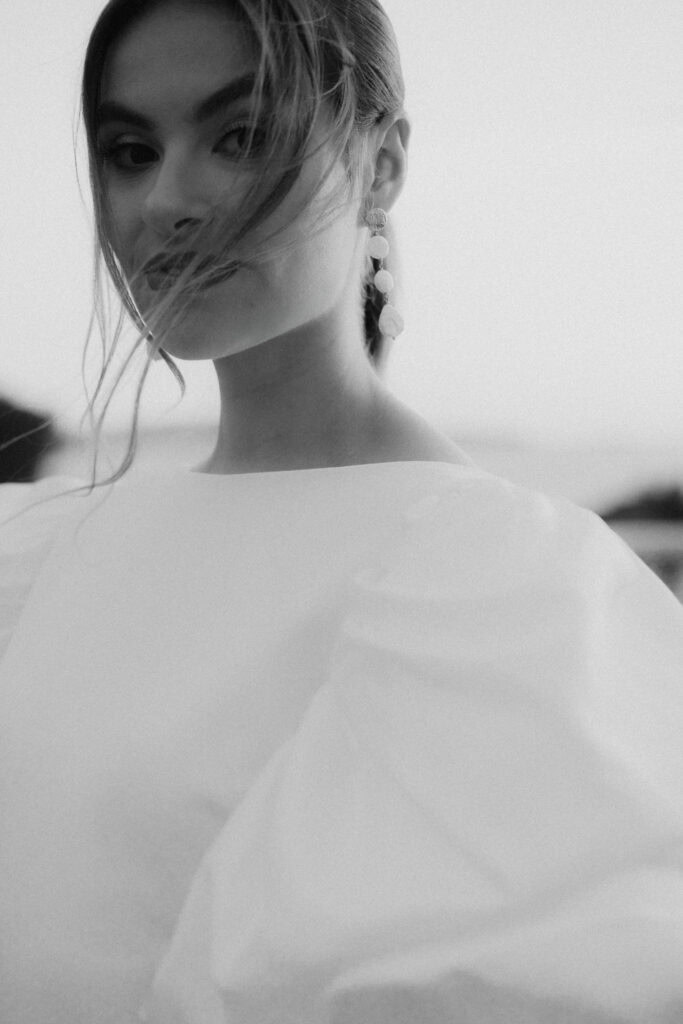 Elegante Frau mit eleganten Ohrringen und wallendem Haar, festgehalten in einem Schwarz-Weiß-Porträt.